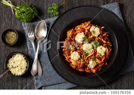 Lasagnette with beef ragu, mushrooms and ricotta cheese in black bowl on dark wooden table  109176356