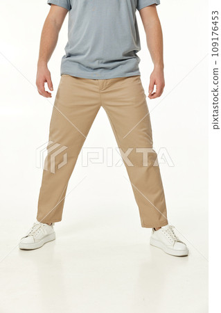 man wearing white sneakers and casual beige pants on studio background, front view man wearing white sneakers and casual beige pants on studio background, front view 109176453