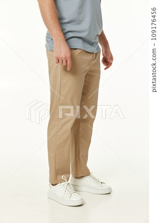 man wearing white sneakers and casual beige pants on studio background. side view man wearing white sneakers and casual beige pants on studio background. side view 109176456