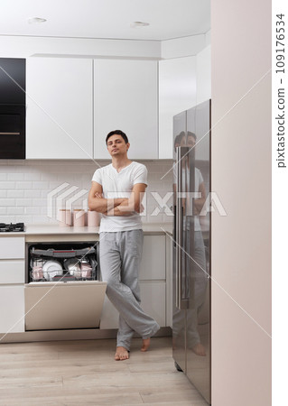 handsome husband man using dishwasher and washing dishes in white modern kitchen handsome husband man using dishwasher and washing dishes in white modern kitchen 109176534