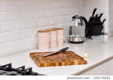 Knife and fresh piece of raw meat on wooden cutting board in modern white kitchen 109176642