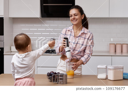 happy mother with her little daughter cooking at white kitchen. baking together happy mother with her little daughter cooking at white kitchen. baking together 109176677