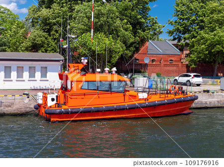 Swinoujscie. A red pilot boat moored at the pier on a sunny day. Swinoujscie. A red pilot boat moored at the pier on a sunny day. 109176916
