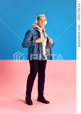Collage. Halves of male portraits. Man in jeans jacket and headphones with legs in trousers over blue pink background. 109178219