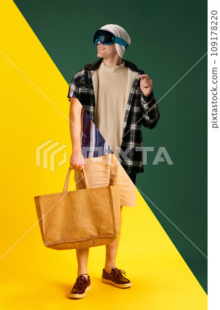 Collage. Halves of male portraits. Summer vs winter seasons. Young man in warm and summer clothes over green yellow background 109178220