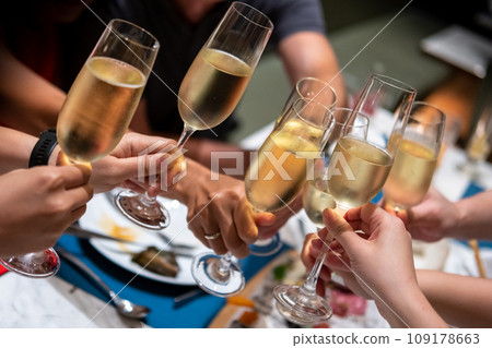 A group of people raise a toast with glasses of Prosecco or sparkling wine on the table A group of people raise a toast with glasses of Prosecco or sparkling wine on the table 109178663