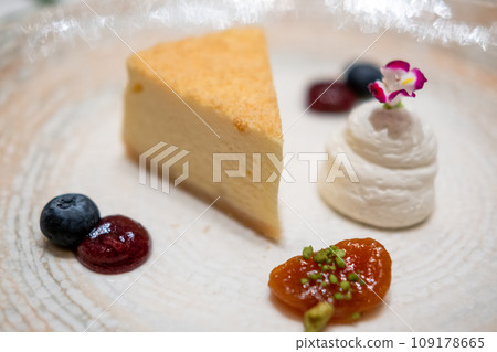 A slice of cheesecake served on plate with berries sauce and whipped cream 109178665