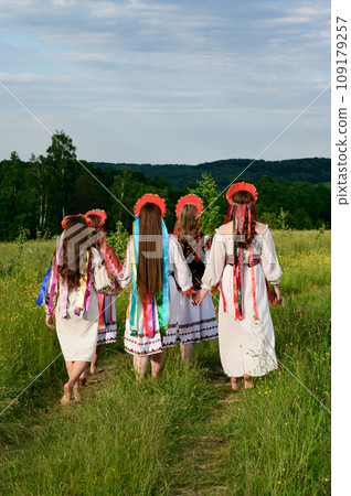 A group of girls are walking in a field, they are dressed in Ukrainian ethnic and national clothes. 109179257