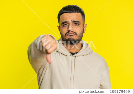 Upset man guy showing thumbs down gesture disapproval dissatisfied dislike negative feedback 109179499