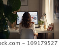 Young woman working from home in front of a computer monitor. The apartment is minimalistic, with plants 109179527