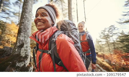 Cheerful group of friends with backpacks for hike walking through autumn forest exploring nature. 109179547