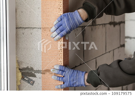 Construction worker fixing fiberglass corner reinforcement mesh during construction process Construction worker fixing fiberglass corner reinforcement mesh during construction process 109179575