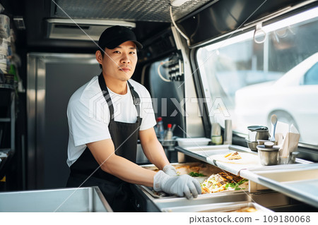 Asian male chef preparing takeaway food in food truck kitchen 109180068