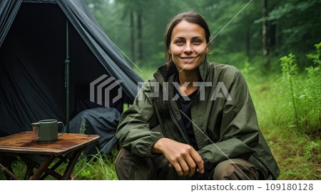 A young Caucasian woman enjoys a morning mug near her tent, alone with nature. A young Caucasian woman enjoys a morning mug near her tent, alone with nature. 109180128