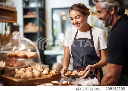 Attractive female seller puts fresh pastries on display and sells them to customers 109180203