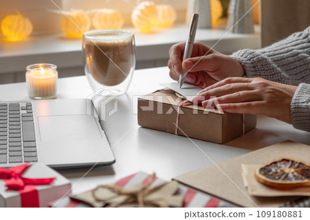 Female buyer makes order on laptop. Woman picking gifts online purchases at cozy home among gift boxes and packages. Winter sales, Black Friday. Christmas discount promotions. Blurred bokeh light. 109180881