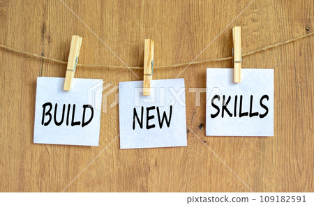Build new skills symbol. Concept word Build new skills on beautiful white paper on wooden clothespin. Beautiful wooden table wooden background. Business, education build new skills concept. Copy space 109182591