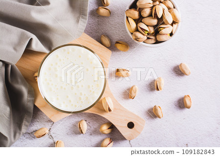 Lactose-free pistachio milk in a glass and nuts on the table top view 109182843