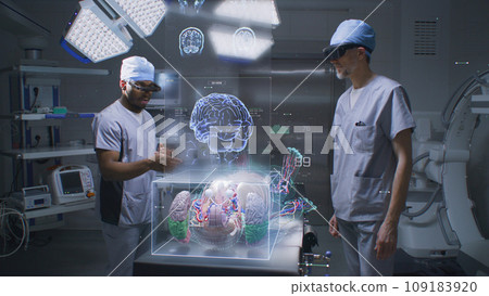 Diverse male surgeons in AR headsets work in operating room Diverse male surgeons in AR headsets work in operating room 109183920