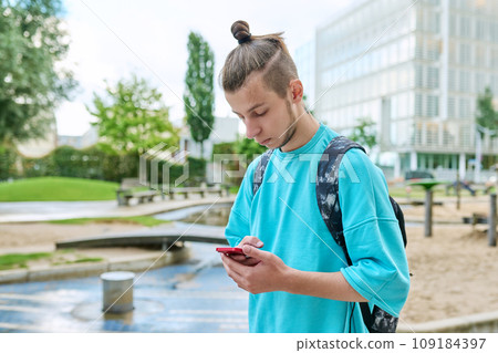 Fashionable young male with backpack using smartphone outdoors in city Fashionable young male with backpack using smartphone outdoors in city 109184397