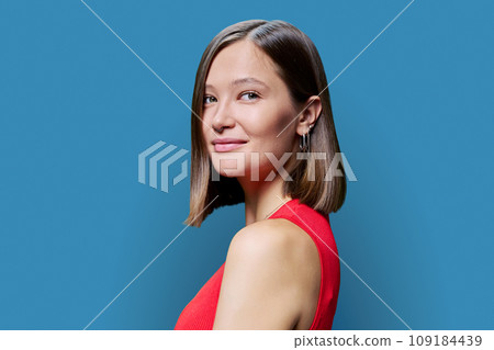 Headshot portrait of young trendy woman looking at camera on blue background 109184439