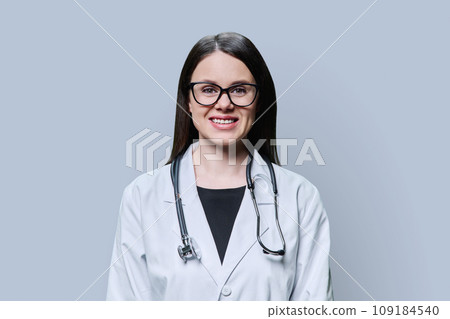 Portrait of smiling female doctor looking at camera on grey background 109184540