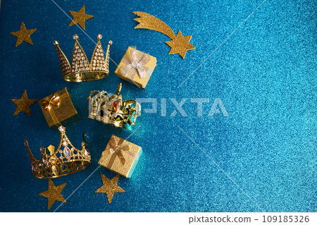 Epiphany Day or Dia de Reyes Magos concept. Three gold crowns and gifts on blue sparkling background Epiphany Day or Dia de Reyes Magos concept. Three gold crowns and gifts on blue sparkling background 109185326