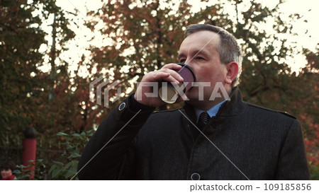 Businessman drinks coffee after meeting with company employees in park Businessman drinks coffee after meeting with company employees in park 109185856