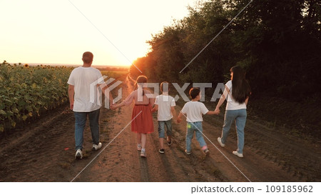 Loving family with children walks joining hands along ground road in evening 109185962