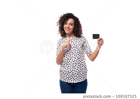 young dark-haired caucasian woman dressed in a blouse holds a plastic card mockup and points her young dark-haired caucasian woman dressed in a blouse holds a plastic card mockup and points her 109187325
