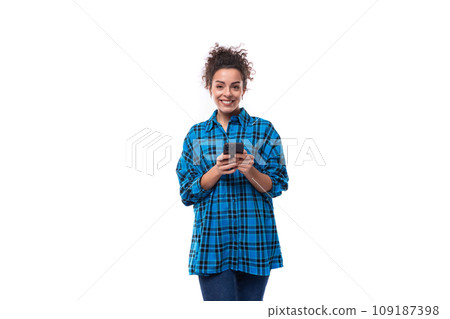 young beautiful european woman with curly hair dressed in a blue plaid shirt is chatting on the young beautiful european woman with curly hair dressed in a blue plaid shirt is chatting on the 109187398
