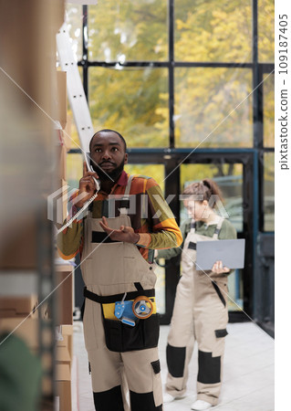 Storage room worker discussing goods stock supply with warehouse manager using landline phone, working at inventory report. Employee checking clients orders in storehouse preparing packages Storage room worker discussing goods stock supply with warehouse manager using landline phone, working at inventory report. Employee checking clients orders in storehouse preparing packages 109187405