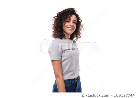 pretty confident authentic young curly brunette woman in gray t-shirt on white background with copy 109187744