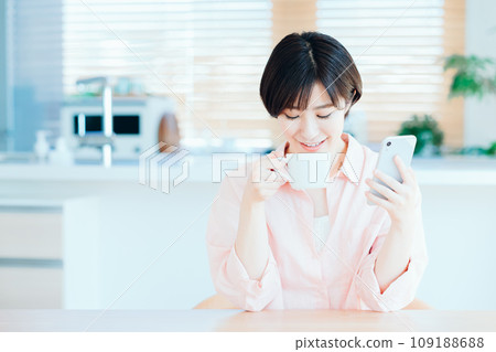 一位女士在客廳放鬆地使用智慧型手機。 109188688