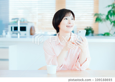 A woman relaxing while using a smartphone in the living room. 109188693