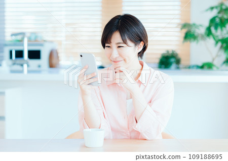 一位女士在客廳放鬆地使用智慧型手機。 109188695