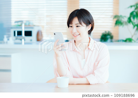 A woman relaxing while using a smartphone in the living room. 109188696