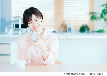 一位女士在客廳放鬆地使用智慧型手機。 109188699