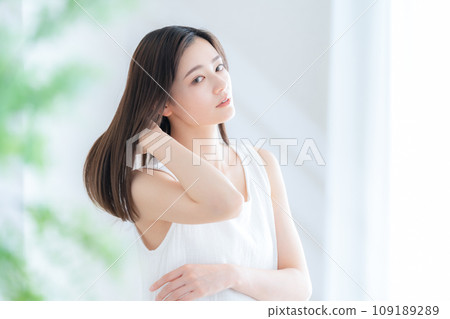 Young woman doing hair care by the window in the living room 109189289
