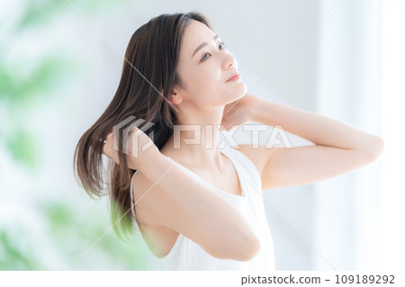 Young woman doing hair care by the window in the living room Young woman doing hair care by the window in the living room 109189292