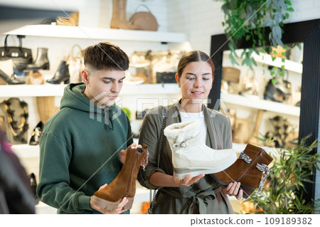 Guy male friend strongly recommends his young woman colleague to pay attention to model of boots 109189382