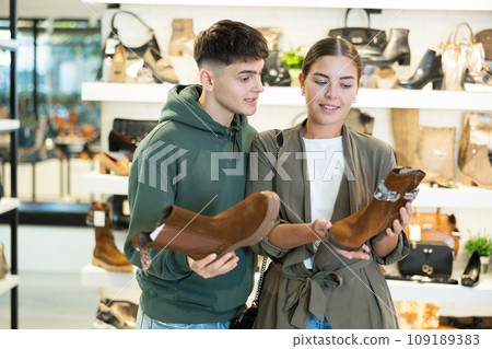 Couple man and woman choosing ankle boots in store 109189383
