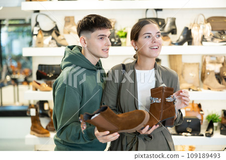 Guy male friend strongly recommends his young woman colleague to pay attention to model of boots Guy male friend strongly recommends his young woman colleague to pay attention to model of boots 109189493