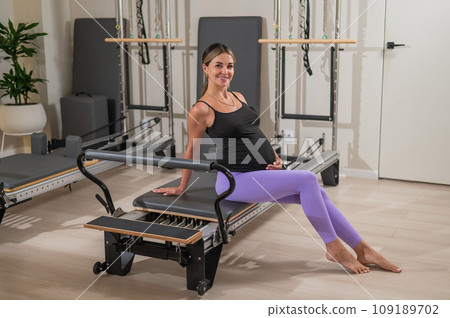 Pregnant woman resting after Pilates on a reformer machine. Pregnant woman resting after Pilates on a reformer machine. 109189702