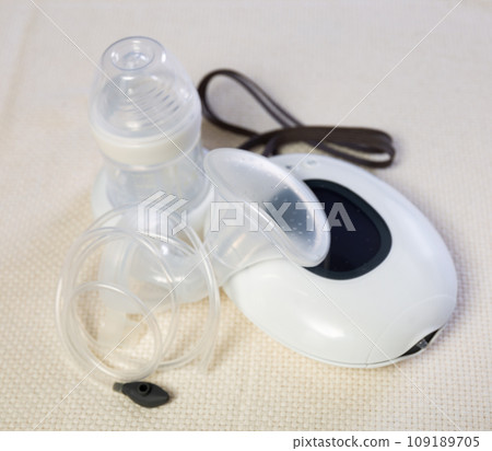Electric mini breast pump lying on cloth 109189705