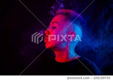 Profile Asian woman with short haircut smoking in neon light. 109189793