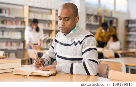 Latin American adult reading books in public library 109189815