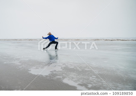 Caucasian woman in a blue sweater skating on a frozen lake. Caucasian woman in a blue sweater skating on a frozen lake. 109189850