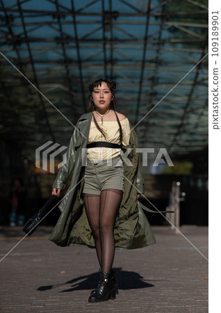 A beautiful Asian woman in shorts and a green leather coat comes out of the subway. A beautiful Asian woman in shorts and a green leather coat comes out of the subway. 109189901