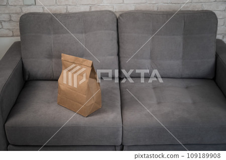 Kraft paper bag with food delivery on gray sofa.  109189908